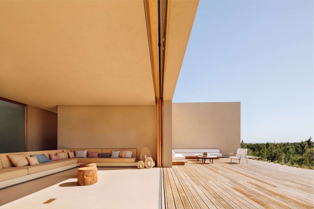 Covered terrace with a built-in sofa and wooden deck opening to the forest