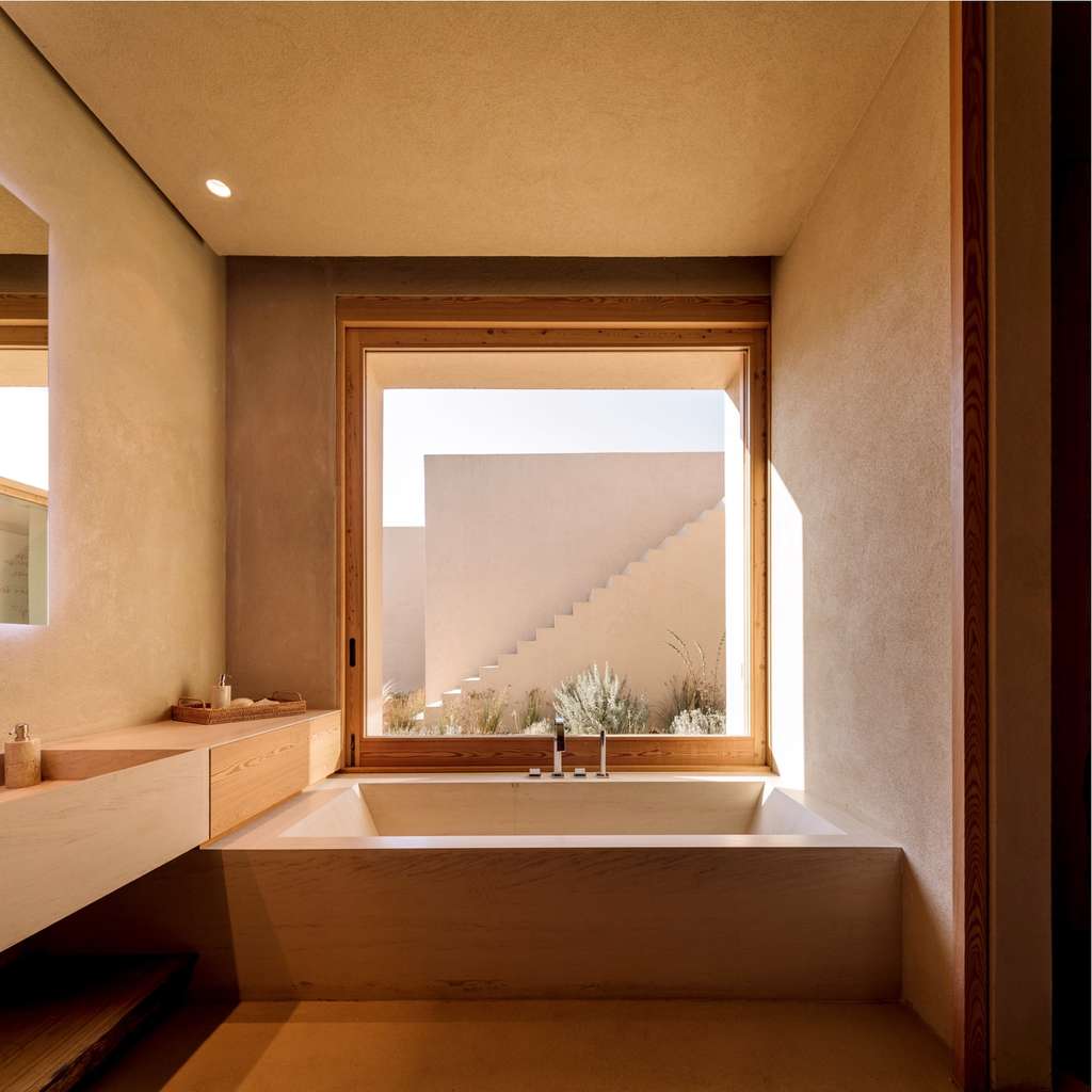 Bathroom with a deep tub beneath a window facing a stairway
