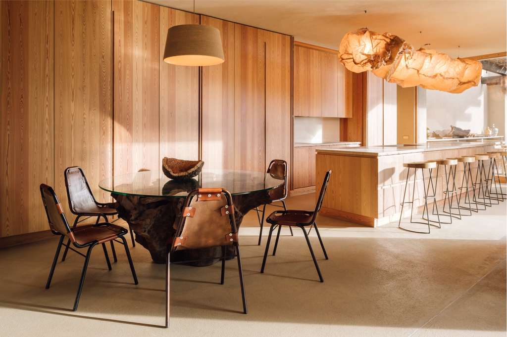 Kitchen and dining area with a round glass table, leather chairs and a hanging light