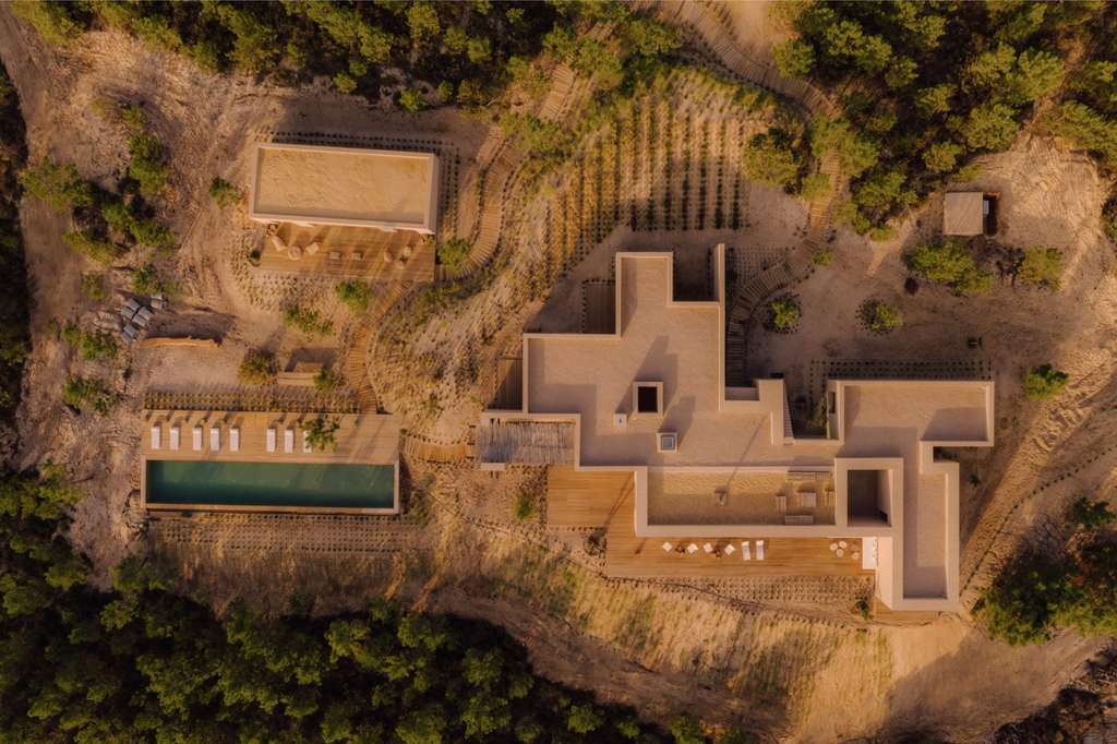 Aerial view of a courtyard house with a pool in a pine forest