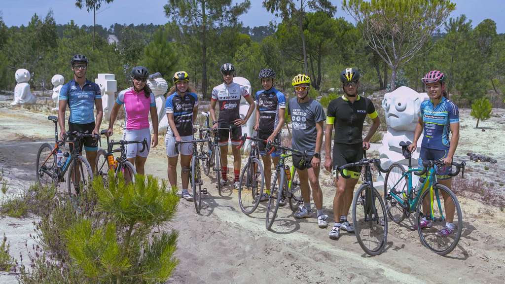 Group of cyclists in team jerseys standing with their bikes in the park