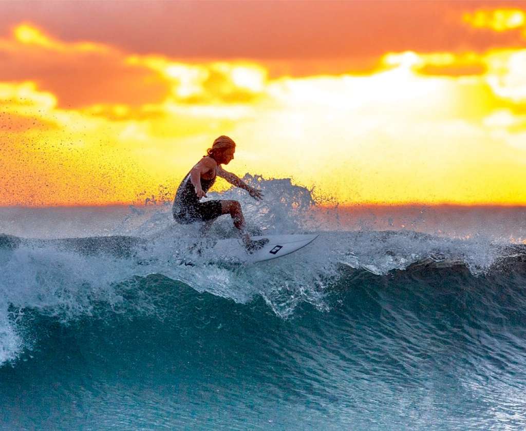 Surfer riding a wave at sunset