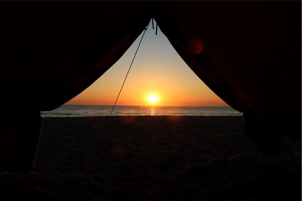 Sunset over the sea seen from inside a dark tent