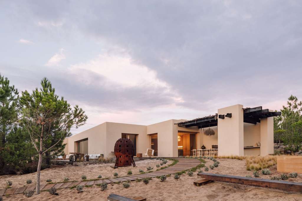 House with a courtyard and a rust-colored sculpture at dusk